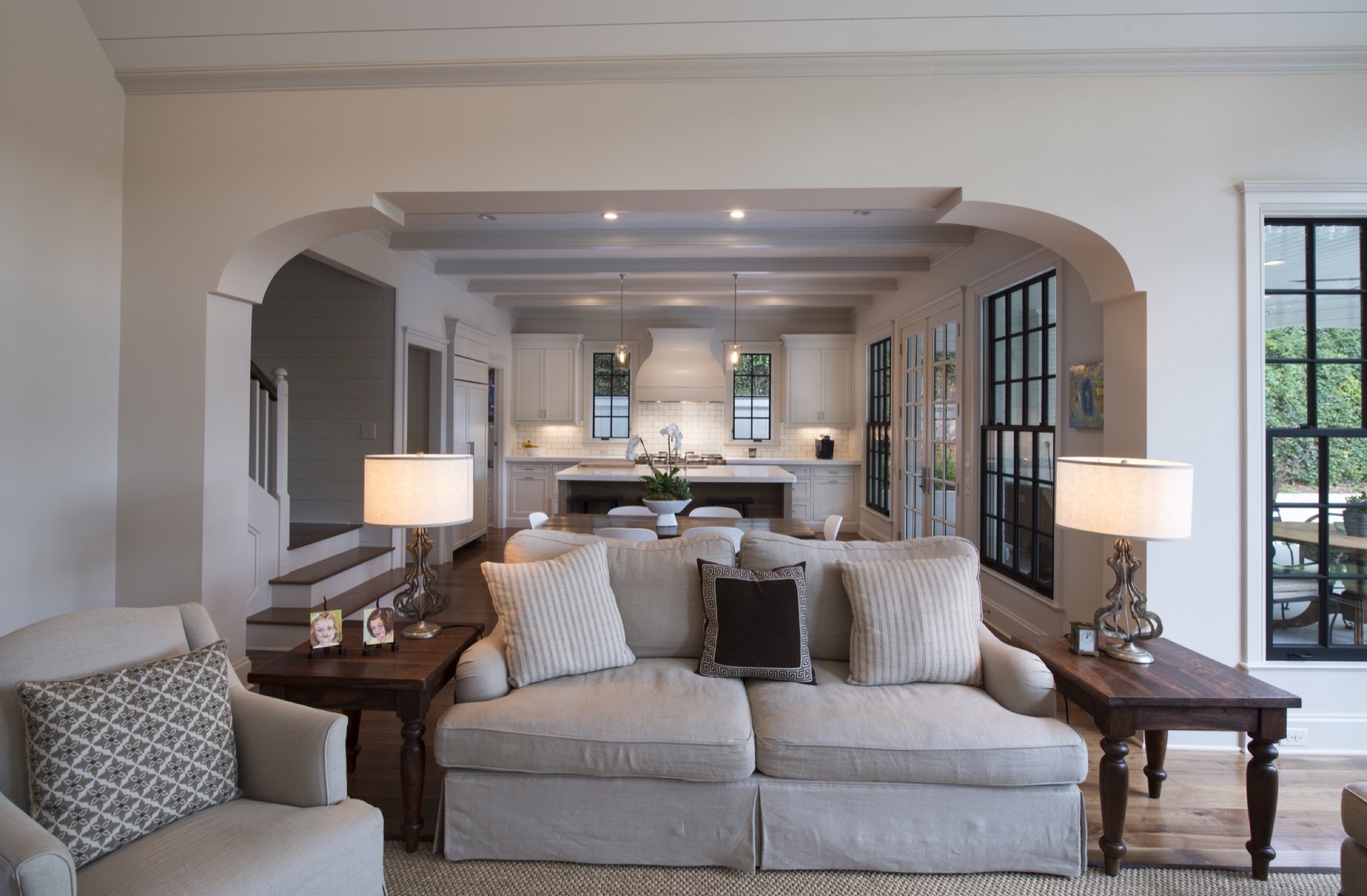 A finished family room opening through an arch to a warm, lit kitchen
