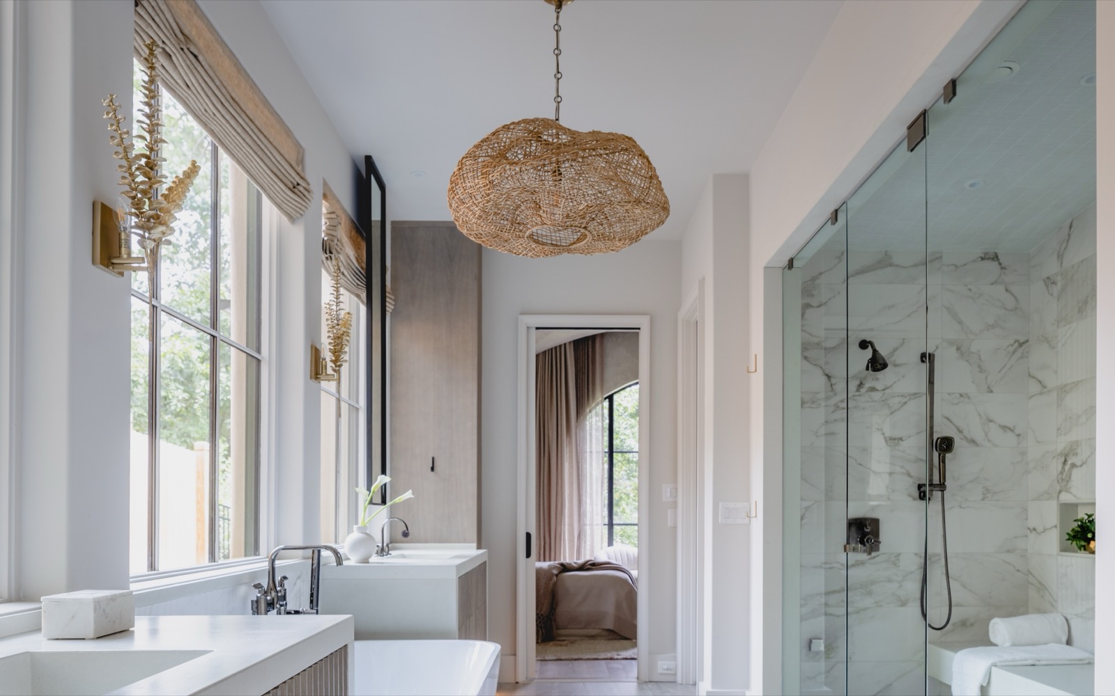 A finished primary bath: freestanding tub, marble shower, and soft light from an arched window